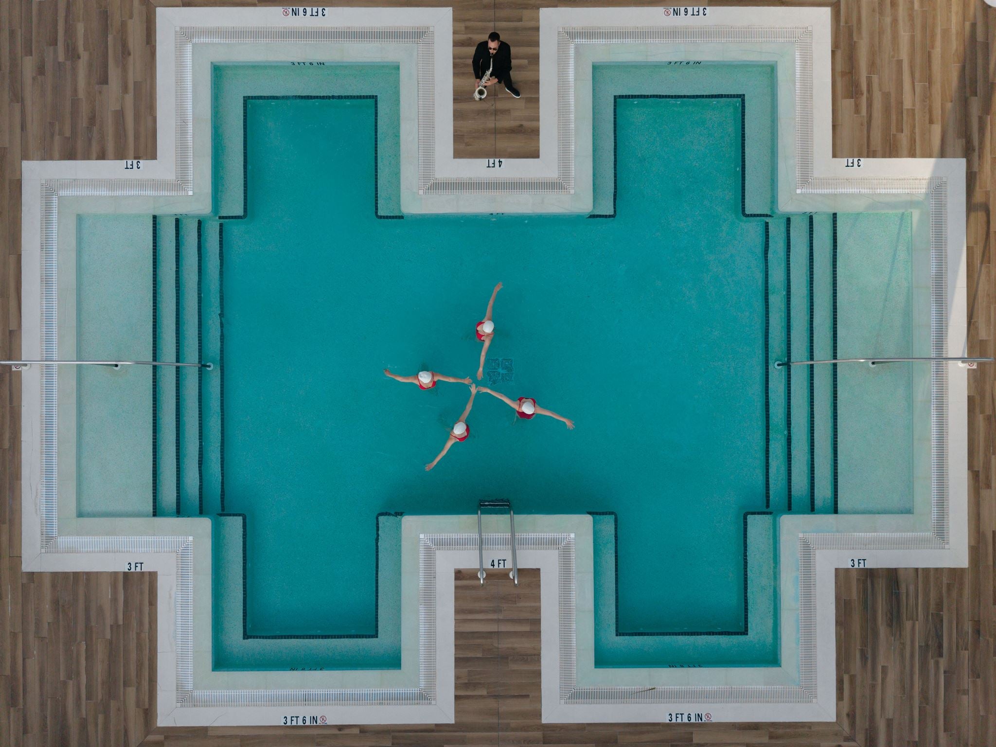 Aerial view of synchronized swimmers in star formation at luxury pool